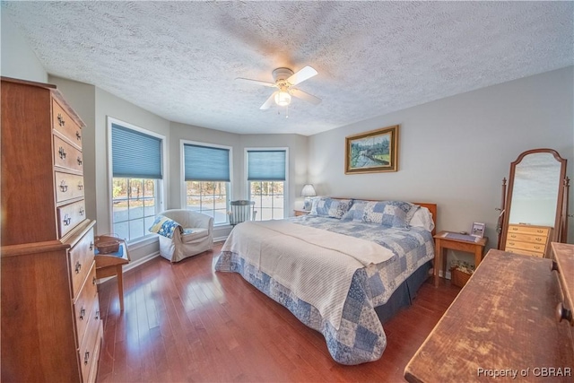 bedroom with a textured ceiling, dark wood-type flooring, and ceiling fan