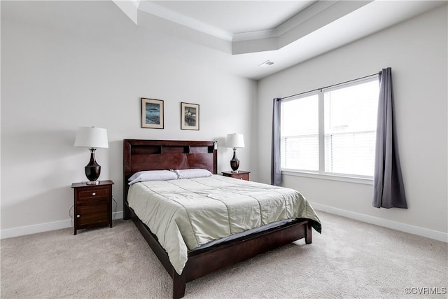 bedroom featuring a raised ceiling, crown molding, and light carpet