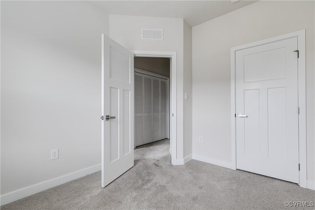 unfurnished bedroom with light colored carpet and a closet