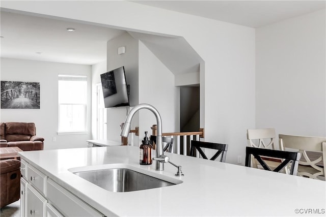 kitchen with sink, white cabinetry, and a kitchen breakfast bar