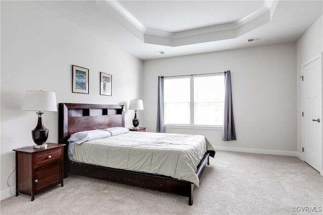 bedroom featuring ornamental molding, light carpet, and a tray ceiling