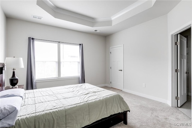 bedroom featuring light carpet and a raised ceiling