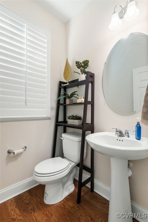 bathroom featuring hardwood / wood-style floors, toilet, and an inviting chandelier