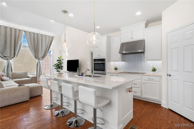 kitchen featuring white cabinetry, a breakfast bar, pendant lighting, and stainless steel oven