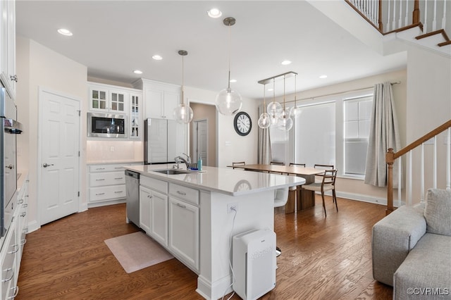 kitchen with white cabinets, an island with sink, stainless steel appliances, and sink