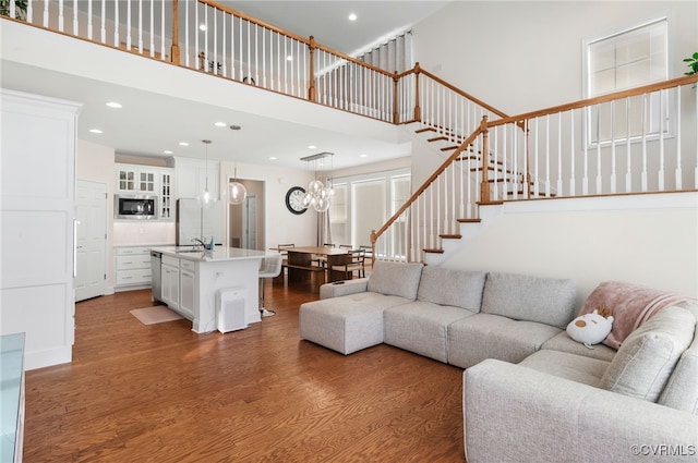 living room featuring sink, a chandelier, a high ceiling, and hardwood / wood-style floors