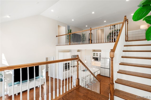 stairway with hardwood / wood-style flooring and lofted ceiling