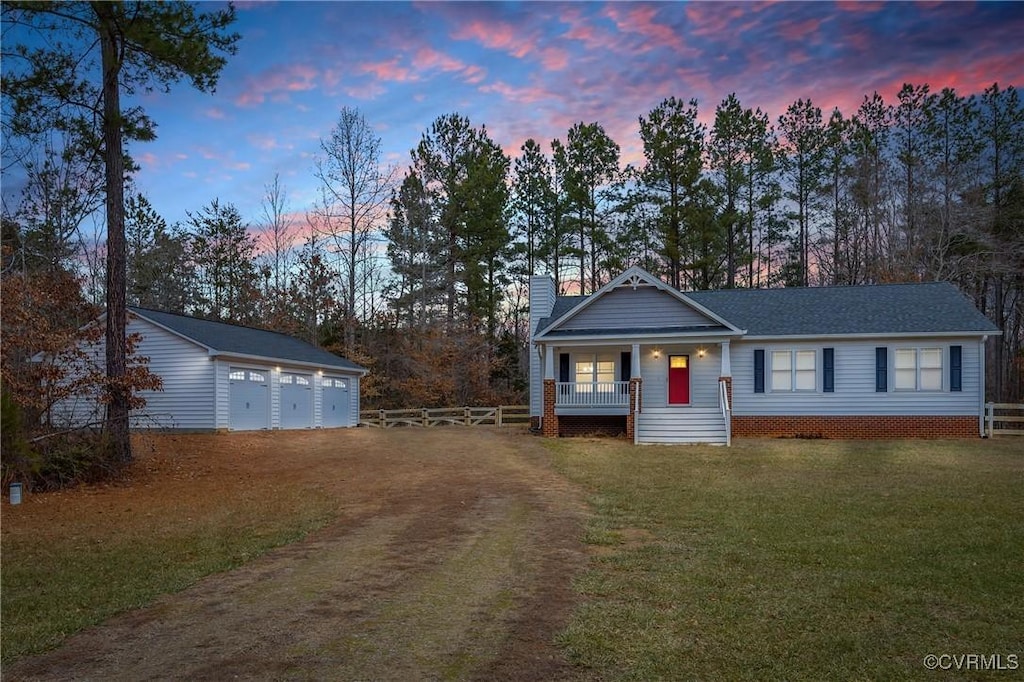 view of front of property featuring a porch, a garage, a lawn, and an outdoor structure