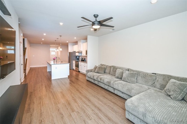 living room featuring sink, light hardwood / wood-style floors, and ceiling fan