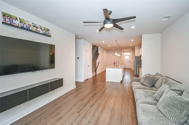 living room featuring sink, light hardwood / wood-style flooring, and ceiling fan