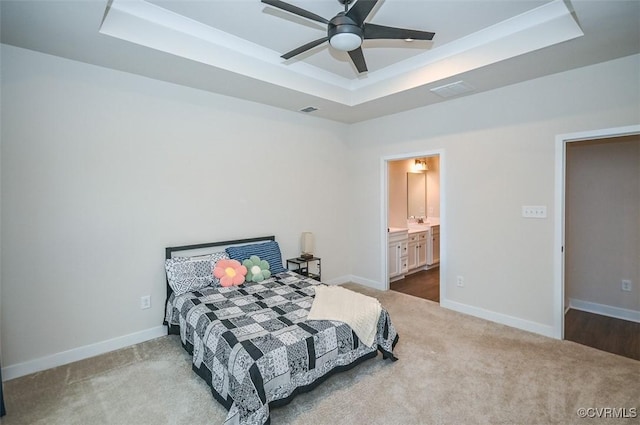 bedroom featuring ceiling fan, ensuite bathroom, and a tray ceiling