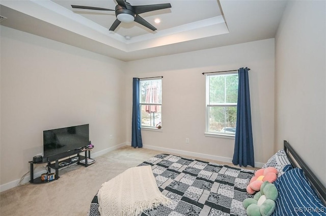 bedroom featuring ceiling fan, a raised ceiling, and light colored carpet