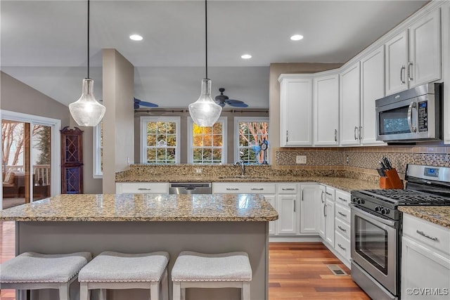 kitchen featuring appliances with stainless steel finishes, pendant lighting, a breakfast bar area, and sink