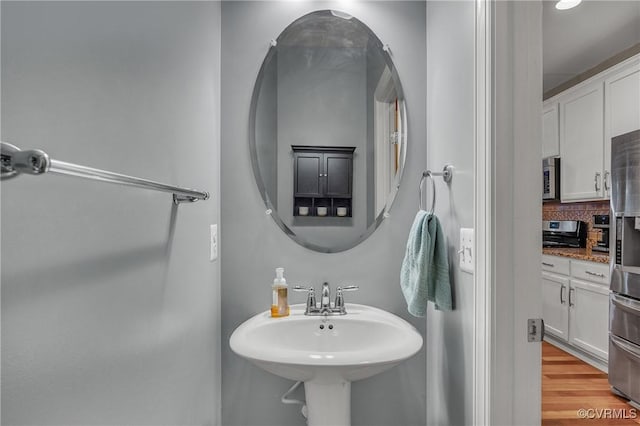 bathroom featuring wood-type flooring, sink, and backsplash