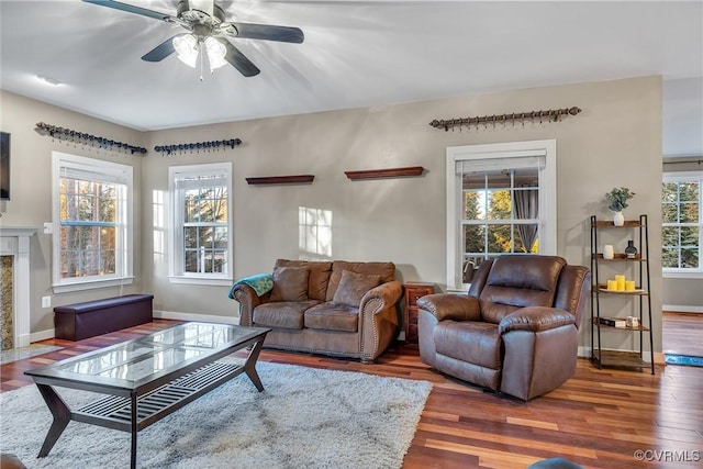 living room with a high end fireplace, plenty of natural light, dark hardwood / wood-style floors, and ceiling fan