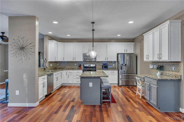 kitchen with stainless steel appliances, white cabinetry, a kitchen island, and a kitchen breakfast bar