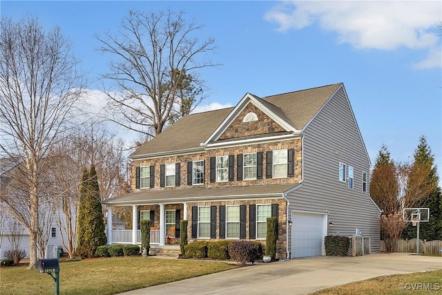 colonial home featuring a garage, a porch, and a front lawn