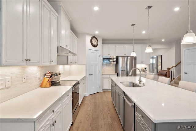 kitchen featuring sink, white cabinetry, appliances with stainless steel finishes, and a large island with sink