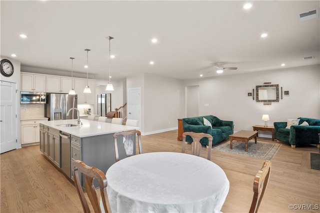 dining area with sink, light hardwood / wood-style flooring, and ceiling fan