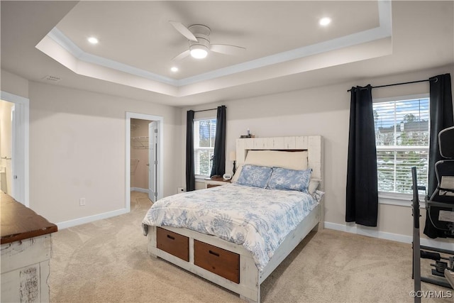 carpeted bedroom featuring ceiling fan, ensuite bathroom, a raised ceiling, a spacious closet, and a closet