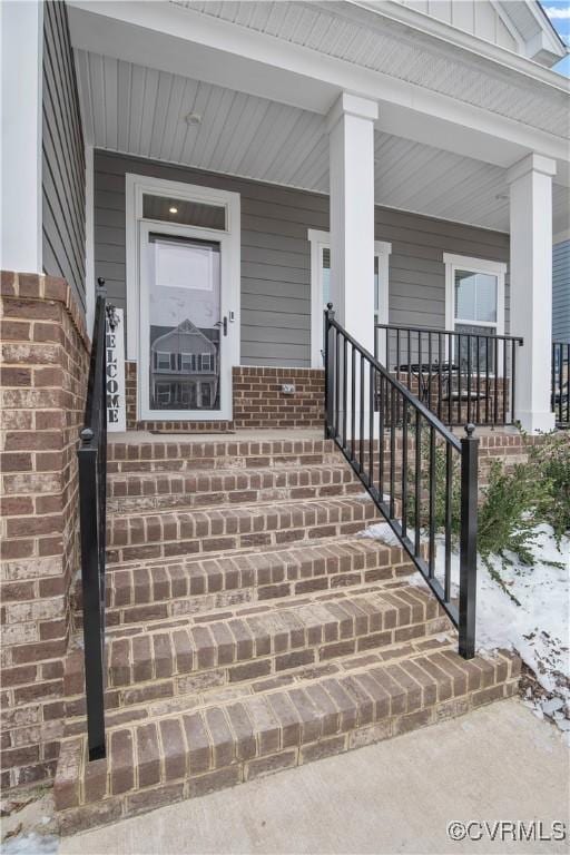 snow covered property entrance featuring a porch