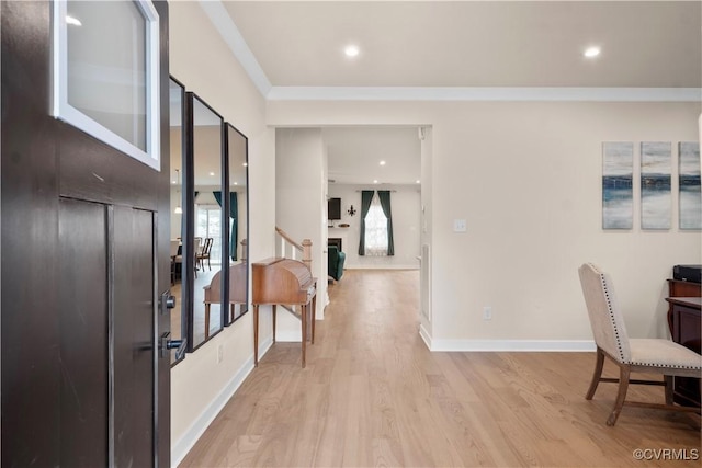 foyer with a wealth of natural light, ornamental molding, and light wood-type flooring