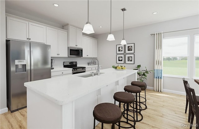 kitchen with pendant lighting, white cabinets, a kitchen island with sink, and appliances with stainless steel finishes