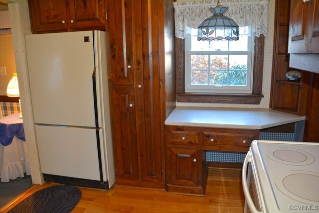 kitchen with hanging light fixtures, white refrigerator, range with electric cooktop, and light hardwood / wood-style flooring