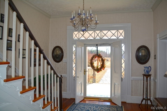 foyer entrance with crown molding, hardwood / wood-style floors, and a notable chandelier