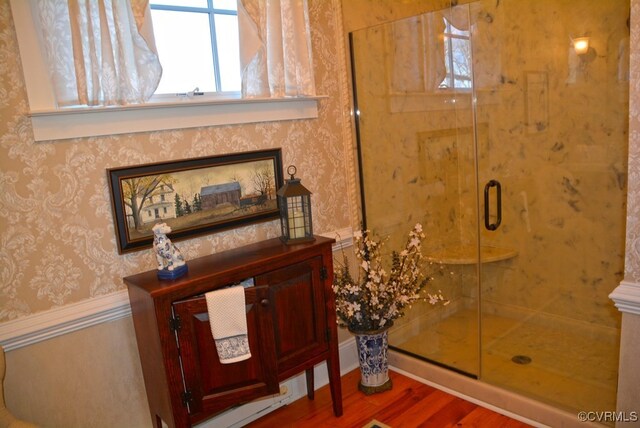 bathroom with hardwood / wood-style flooring and a shower with shower door