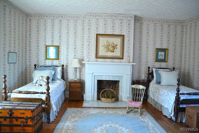 bedroom featuring hardwood / wood-style floors, a textured ceiling, and a high end fireplace