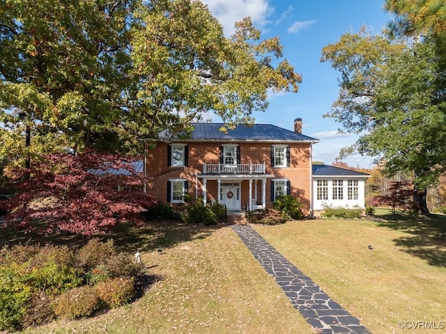 colonial-style house with a balcony, covered porch, and a front lawn