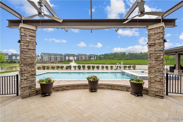 view of swimming pool with a patio, ceiling fan, and a water view