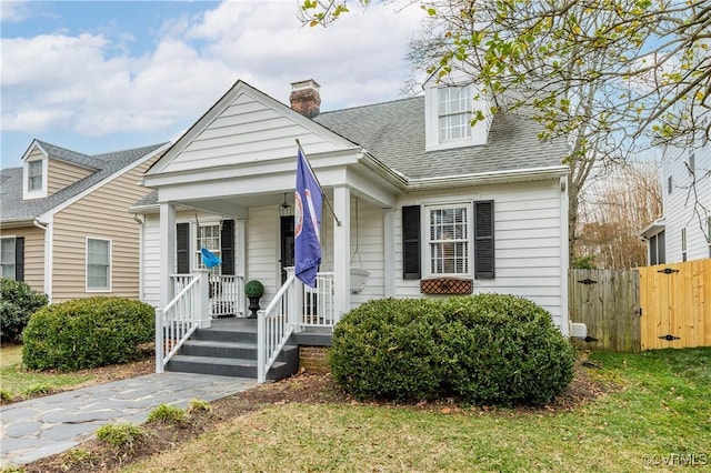 cape cod house with covered porch and a front lawn