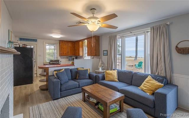 living room featuring ceiling fan, light wood-type flooring, and plenty of natural light