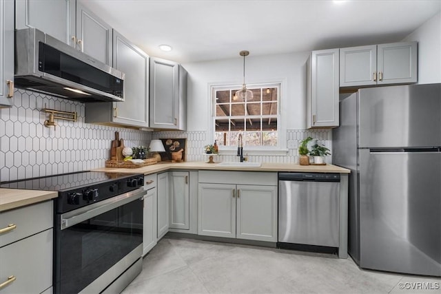 kitchen with sink, gray cabinetry, tasteful backsplash, decorative light fixtures, and stainless steel appliances