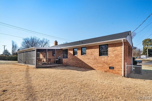 back of property featuring a sunroom and a lawn