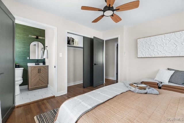 bedroom with ceiling fan, ensuite bathroom, dark hardwood / wood-style floors, and sink