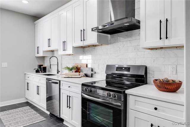 kitchen featuring sink, white cabinetry, dark tile patterned flooring, wall chimney range hood, and stainless steel appliances