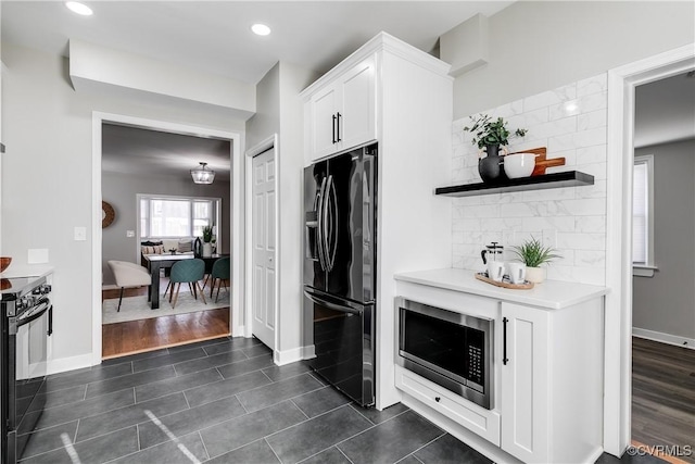 kitchen featuring dark tile patterned flooring, black appliances, white cabinetry, and tasteful backsplash