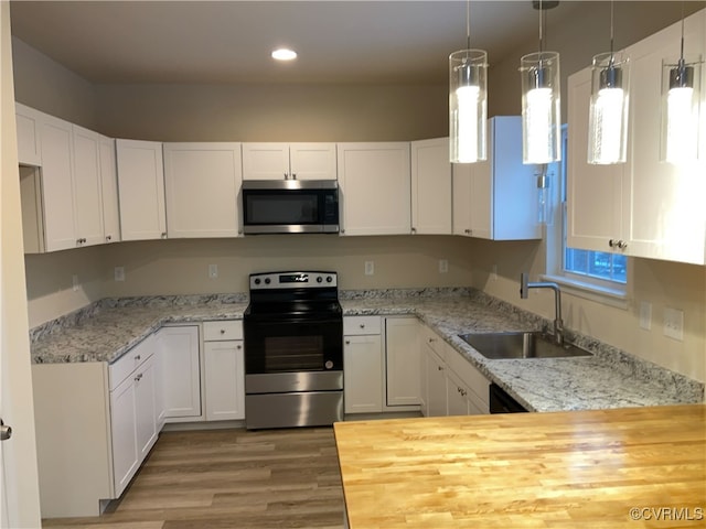 kitchen featuring pendant lighting, sink, stainless steel appliances, and white cabinets