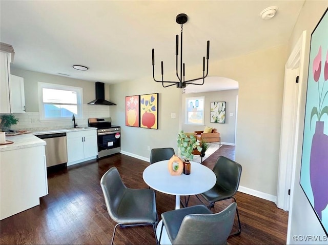 dining area featuring dark wood-type flooring, a healthy amount of sunlight, an inviting chandelier, and sink