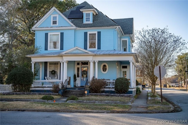 victorian home featuring covered porch and solar panels