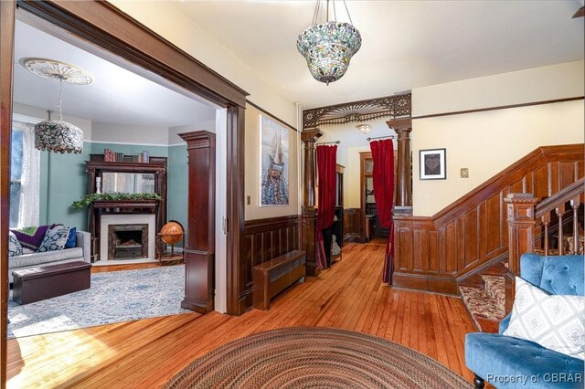 corridor featuring light wood-type flooring and ornate columns