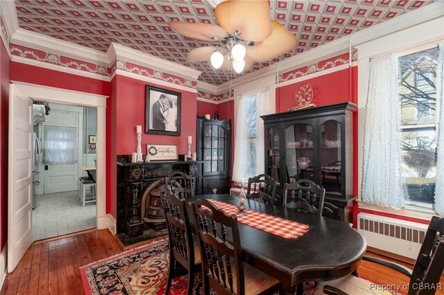 dining area with radiator heating unit, hardwood / wood-style floors, ceiling fan, and ornamental molding