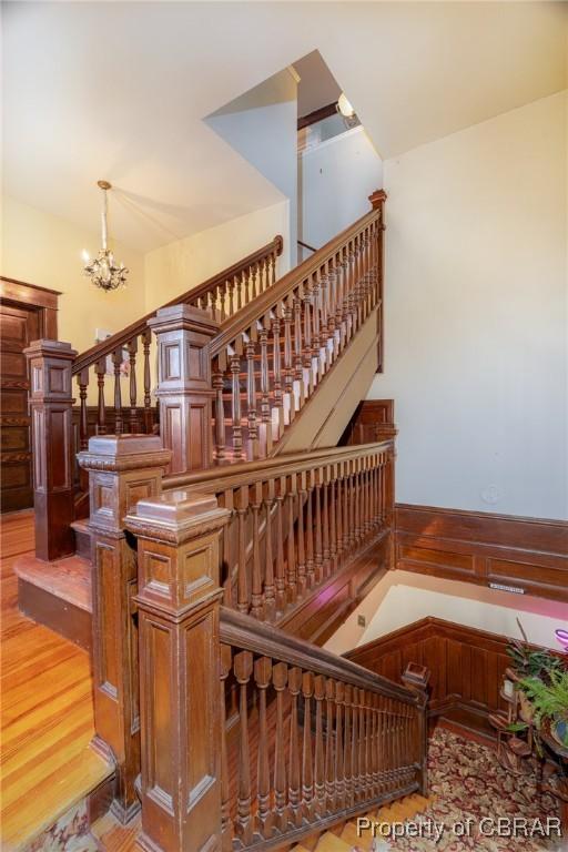 stairs with a notable chandelier and wood-type flooring