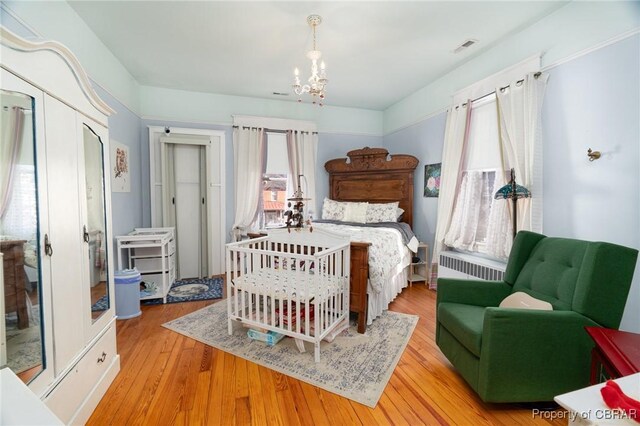 bedroom with light hardwood / wood-style floors, multiple windows, and an inviting chandelier