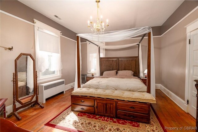 bedroom featuring a notable chandelier, hardwood / wood-style flooring, and radiator heating unit