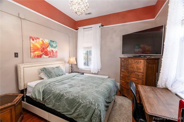 bedroom featuring wood-type flooring and a notable chandelier