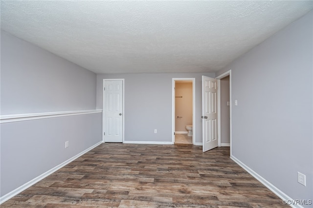 spare room with a textured ceiling and dark hardwood / wood-style flooring